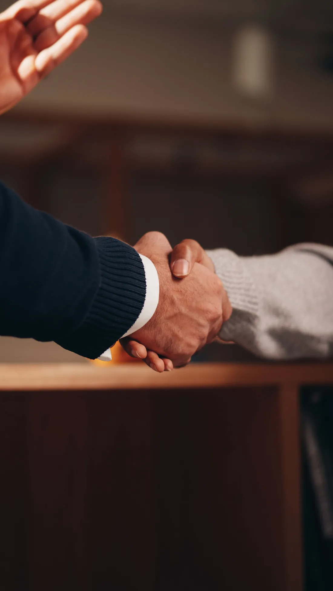 Zwei Personen geben sich die Hand über einem Tisch