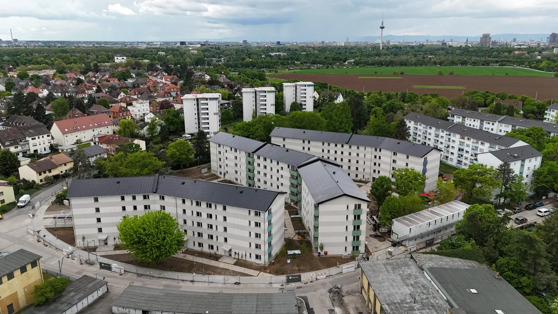 Luftaufnahme mehrerer Wohnblocks und Hochhäuser mit Stadtskyline im Hintergrund